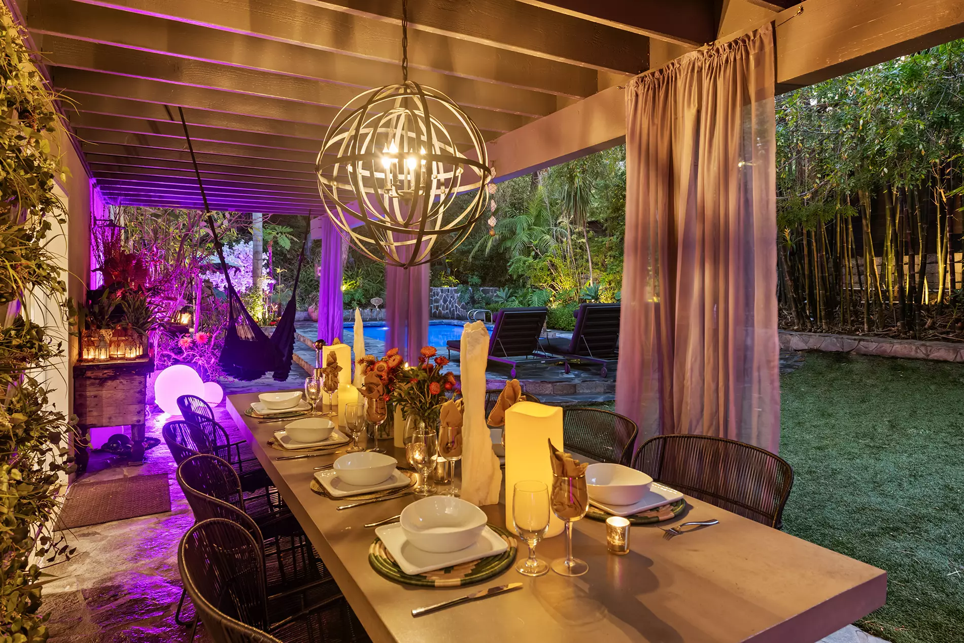 Woodland Hills vacation rental outdoor dining area with ambient lighting and pool, managed by LALuxuryBnB